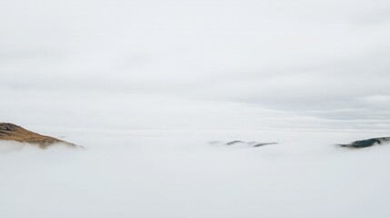 Misty mountain landscape with rolling hills partially obscured by fog.