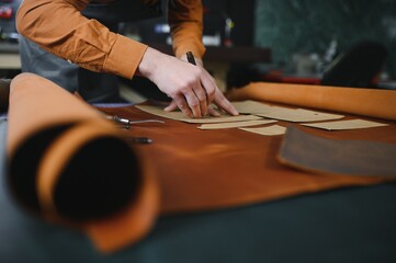 Production process. Young focused experienced master craftsman makes leather goods at his workplace