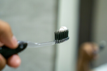 Close up of a hand holding a toothbrush with a toothpaste on the top. Oral cleaning concept.