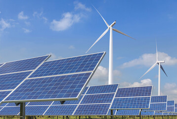 Rows array of Solar panels and wind turbines generating electricity in hybrid power plant systems station , alternative clean energy renewable efficiency