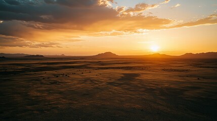 Stunning sunset over a vast, flat desert landscape with distant mountains.
