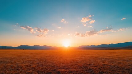Obraz premium A large, empty field with a bright orange sun in the sky