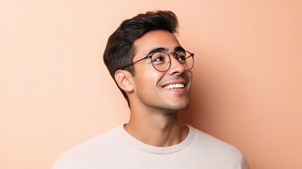 Obraz premium Young Hispanic Man with Glasses Smiling Against a Peach Background
