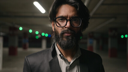 Fototapeta premium Stressed frustrated Indian man in underground parking lot suffering from tension disappointed male businessman feeling headache upset by stress crisis business problem failure bankruptcy heartbroken