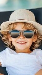 Fototapeta premium Happy child wearing sunglasses and a hat while sitting comfortably indoors
