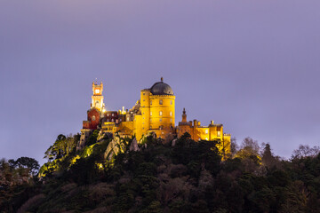 Fototapeta premium Illuminated Pena Palace in Sintra at Evening Twilight and Cloudy Sky. Portugal. Blue Hour