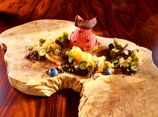 Himbeersorbet Eiskugel mit Waldfruechten und Zutaten, Eiskugel, Dessert, Holzuntergrund, Schokodeko,
