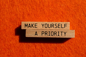 Obraz premium Make yourself a priority message written on wooden blocks with orange background. Conceptual make yourself a priority symbol. Copy space.