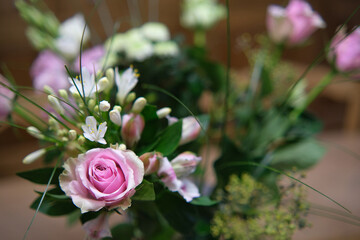 Close-up of a rose in a bouquet of flowers on a wooden table.
