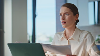 Anxious woman reviewing papers at workplace closeup. Displeased businesswoman