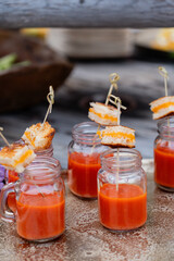 small mason jars filled with tomato soup and topped with mini grilled cheese bites on skewers at wedding cocktail hour