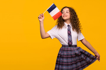 Girl waving French flag playfully in a school uniform. Foreign language learning concept
