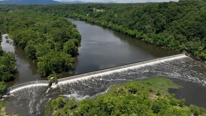 Fototapeta premium Beautiful waterfall on warm summer day on James River at Lynchburg, VA historic southern town green trees blue sky with clouds