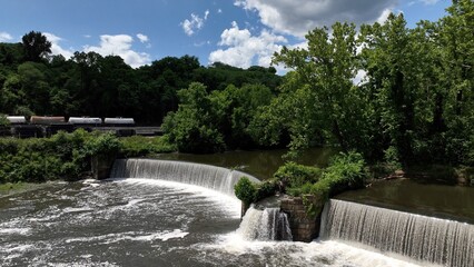 Beautiful waterfall on warm summer day on James River at Lynchburg, VA historic southern town green trees blue sky with clouds