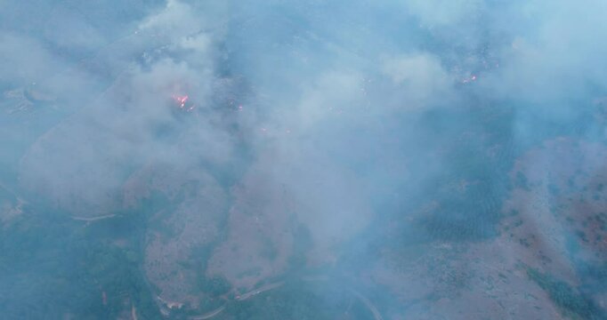 A blue sky with smoke from burning agriculture bush fields in the background, aerial view