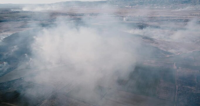 Sky with smoke from burning agriculture bush fields in the background, aerial view