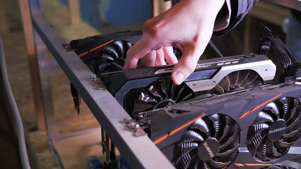 Technician's hand installing graphics card into custom-built mining rig for cryptocurrency mining...