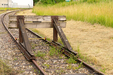 Old weathered wooden and steel buffer stop at the end of a railroad track.