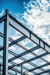A modern steel framework against a bright blue sky with wispy clouds, symbolizing progress and innovation in architecture and construction.