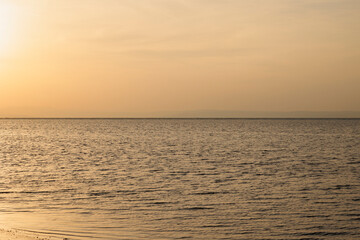 Obraz premium alba sul mare calmo, lungo la costa vicino alla città di Grado, nell'Italia nord orientale, con vista fino all'orizzonte, con un cielo coperto dalla foschia