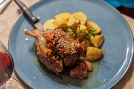 dettagli di un piatto a base di stinco di maiale e patate al forno