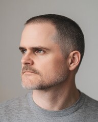 Obraz premium Thoughtful Portrait of a Man with Short Graying Hair and a Gray Sweatshirt Against a Neutral Background