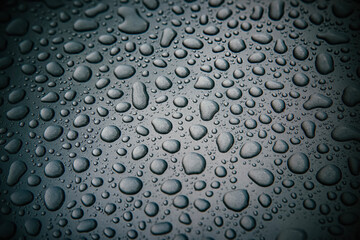 Water drops on a silver metal polished surface. Water-repellent coating for car body.  Large sparkling water drops on a dark silver background.