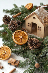 christmas arrangement centerpiece close-up with dried oranges, cinnamon and pine branches around little wooden houses