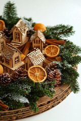 christmas arrangement centerpiece close-up with dried oranges, cinnamon and pine branches around little wooden houses