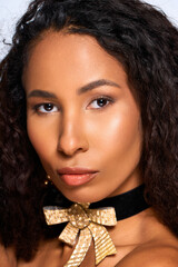 Captivating woman adorned with golden accents exudes confidence and elegance in a studio portrait