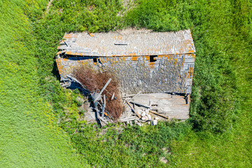 A dilapidated building sits in a field of grass