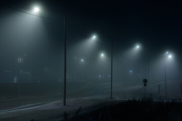 View of empty dark night blue foggy misty rainy city road, low poor visibility due to season. Seasonal bad rainy weather, accident danger, warning