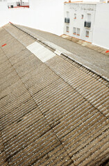 Asbestos cement roof on an old industrial building surrounded by houses. Danger of asbestos contamination. Asbestos is a carcinogenic material. Corrugated fibro sheets