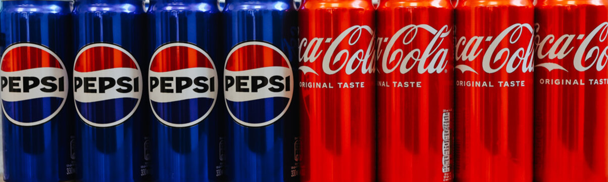 Kyiv, Ukraine - November 5, 2024: Close-up of neatly arranged Pepsi and Coca-Cola cans, showcasing a vibrant contrast of their iconic blue and red branding