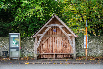 A rural wooden bus shelter and defibrillator in Rowlands Castle, Hampshire, England.