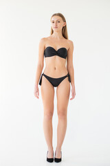 Fototapeta premium young woman in black lingerie and underwear posing on grey background. model agency test shoot