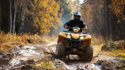 A man in a helmet rides a yellow ATV on a muddy road. The man was wearing a black jacket and trousers