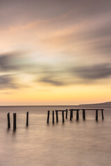 Obraz premium A Long Exposure Panoramic of Abandon old derelict pier foundations leading in to the sea at Sunrise, from Watudodol Beach Banyuwangi.