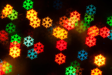 Christmas festive background with Christmas glowing color lights in form of snowflakes, blurred bright Christmas abstract bokeh