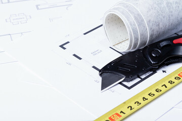 Laying flooring. Linoleum, a knife and a house plan on the builder's table. Taking measurements for laying the floor..