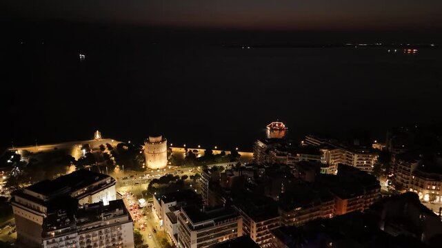 Nighttime view of Thessaloniki's waterfront with illuminated landmarks and calm waters