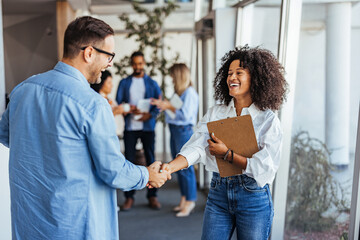 Smiling Colleagues Shaking Hands in Modern Office Environment