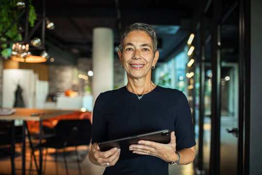 Confident businesswoman holding tablet in modern office environment