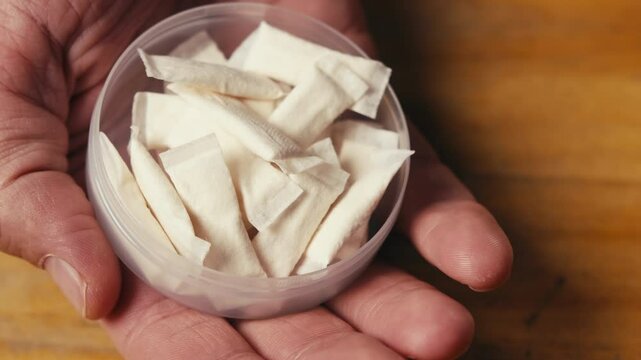 Snus nicotine tobacco close up, pack of tobacco for gum. unhealthy addiction. Man opening box with snus and taking one. 