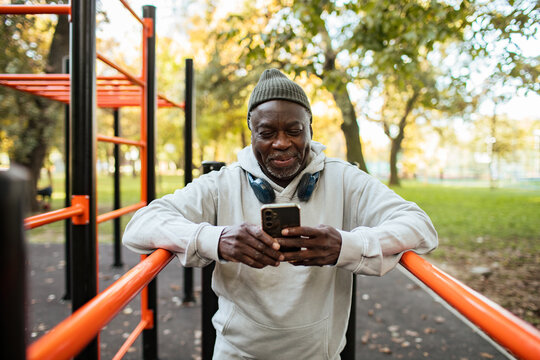 Senior man using smartphone at outdoor fitness park