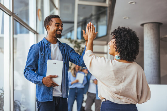 Happy Colleagues High-Fiving in a Bright Office Setting