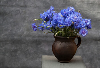 Bouquet of cornflowers in a clay mug
