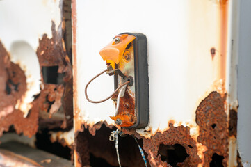 Close-up of a rusted truck surface with a broken amber light and exposed wires, showing decay, neglect, and industrial wear over time.