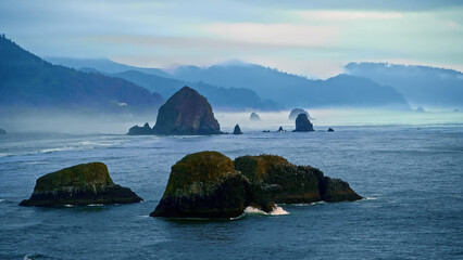 Majestic, large rocks sticking out of Oregon coast with foggy distance - wide shot