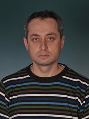 Fototapeta premium The image depicts a close-up of a man with a serious, thoughtful expression. His piercing gaze, dark features, and striped sweater create an aura of introspection and analytical focus. 